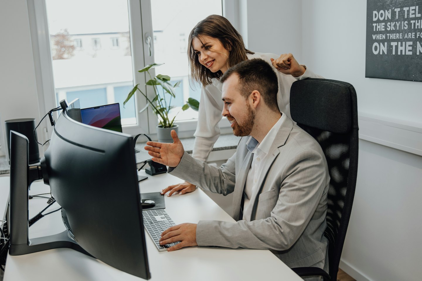 Due colleghi collaborano a una scrivania in un ufficio moderno.